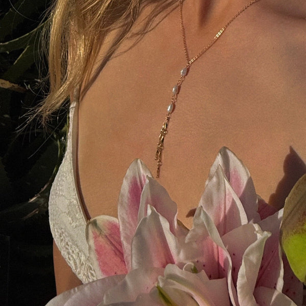 Person wearing a delicate gold necklace with a blurred background