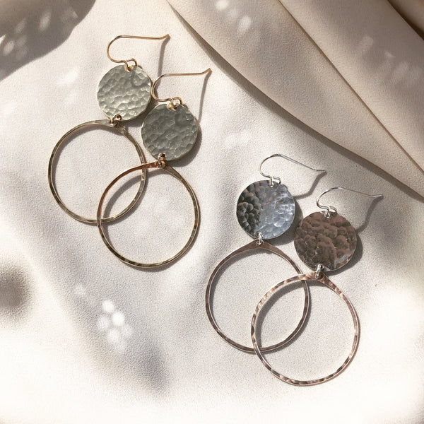 handcrafted hoop earrings with hammered discs, in gold filled and sterling silver, laying in the sunlight