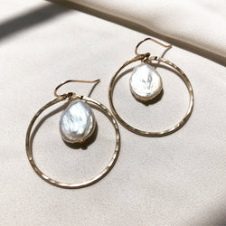 handmade, freshwater pearl earrings with gold hoops, displayed on a fabric background 