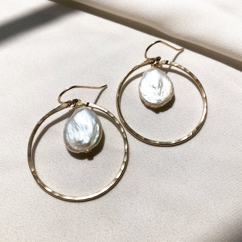 handmade, freshwater pearl earrings with gold hoops, displayed on a fabric background 
