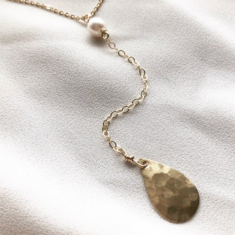 14k gold-filled chain lariat necklace with  drop detail featuring freshwater pearl and gold water droplet , on a cloth background 