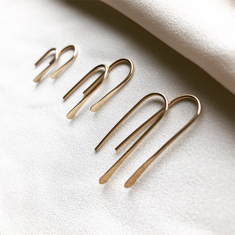 three pairs of handmade, gold threader earrings, displayed on a cloth background 