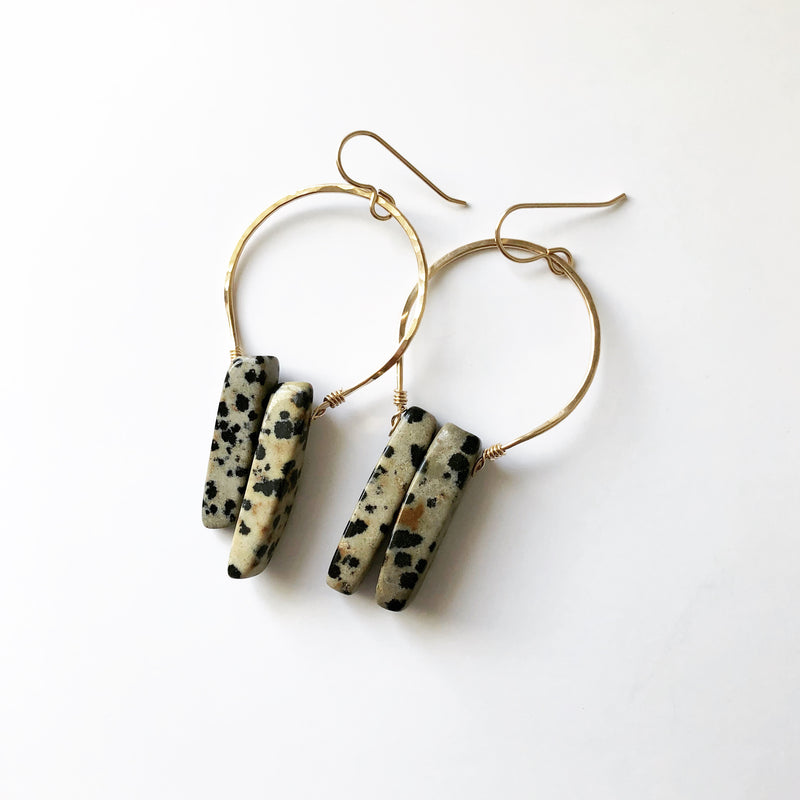 handmade earrings, gold earrings which hold a Dalmatian jasper stone, placed on a white background